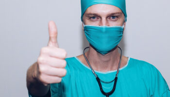 nurse in mask giving thumbs up sign