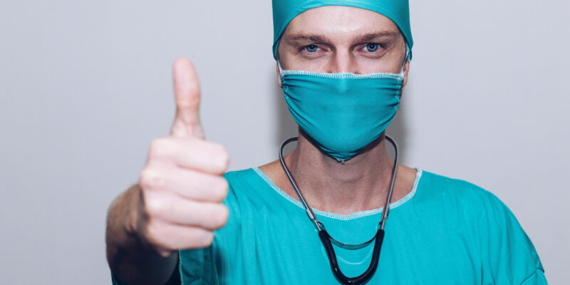 nurse in mask giving thumbs up sign
