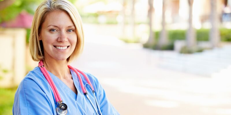 Female nurse smiling for a photo outside