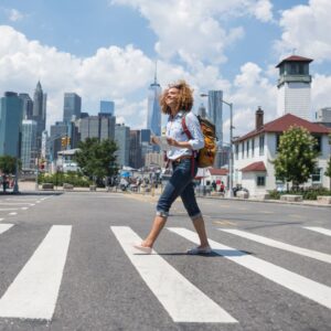 Woman on a crosswalk with a big city in the background
