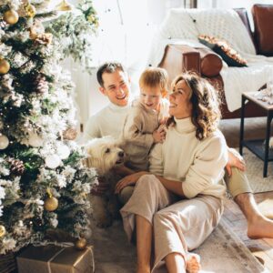 Parents and their young child smiling by their Christmas tree