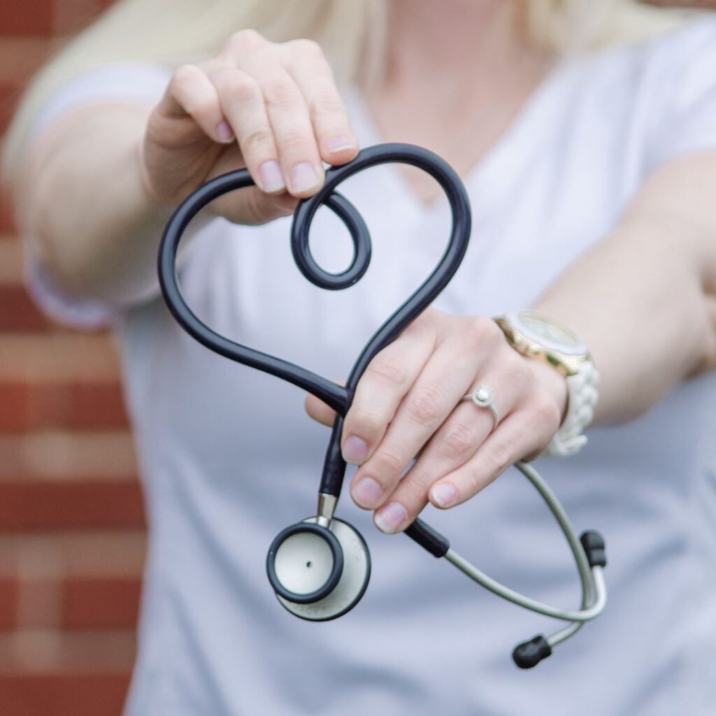 Nurse holding a stethoscope in the shape of a heart.