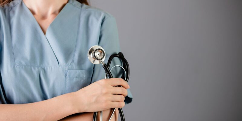 Female nurse standing with her arms crossed and holding a stethoscope in one hand.