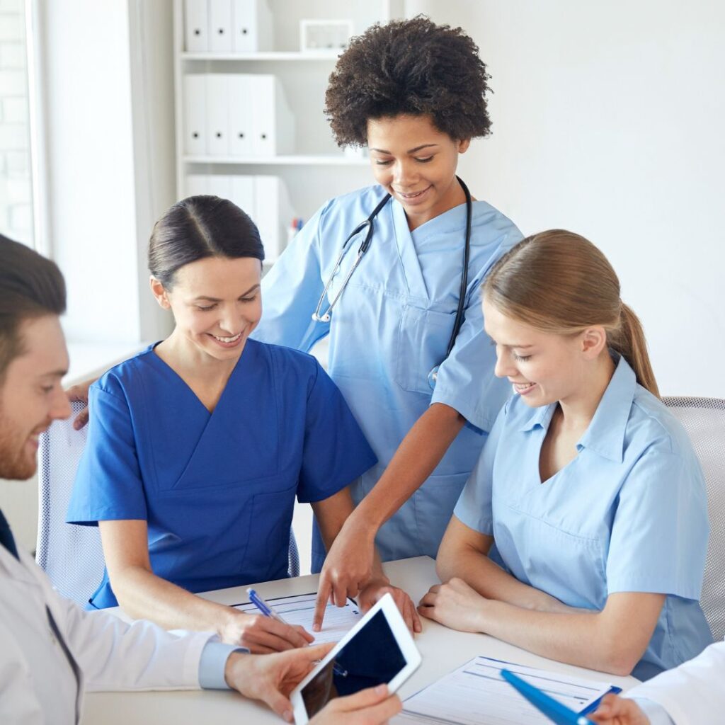 Nurses surrounding a table looking at documents. 