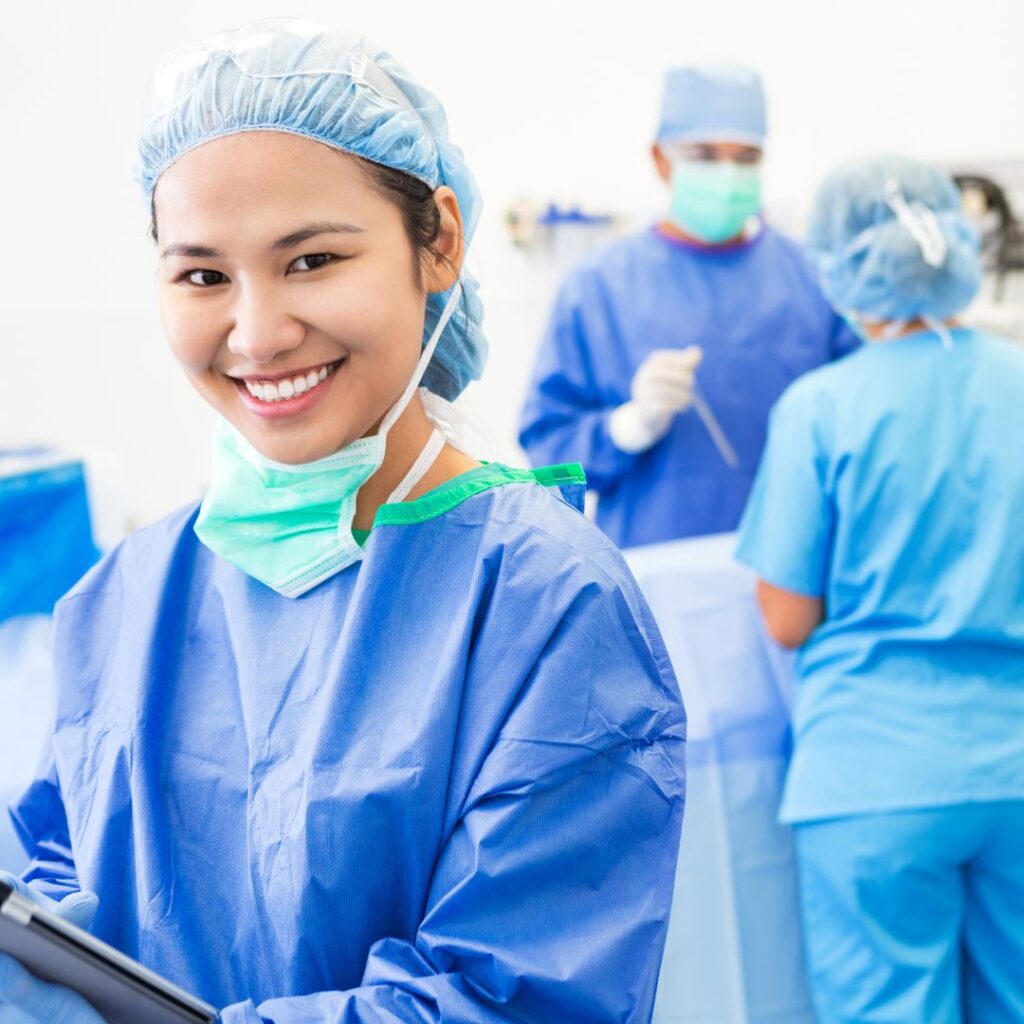 Female nurse in the operating room with her mask pulled down, smiling. 