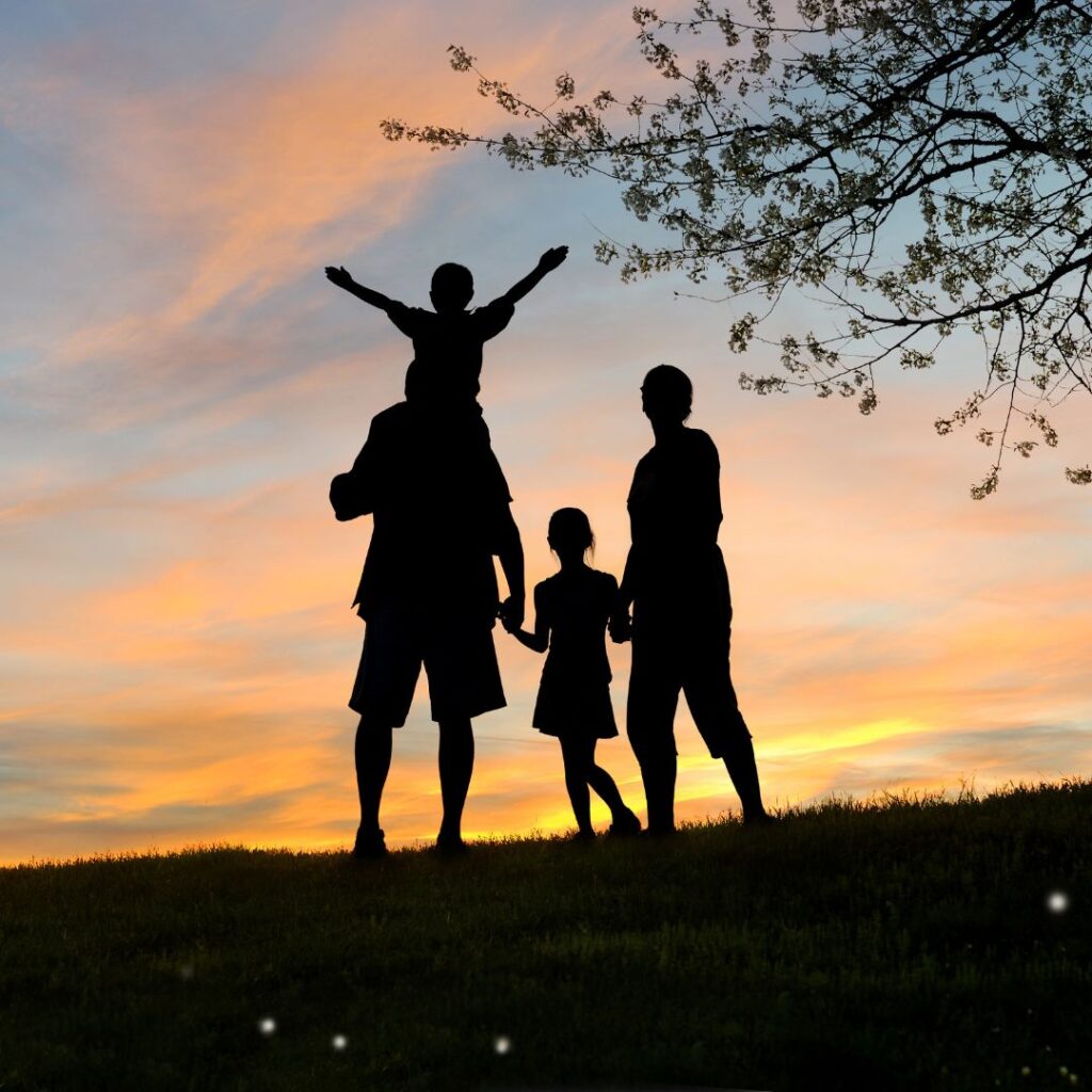 Family silhouette watching sunset together 